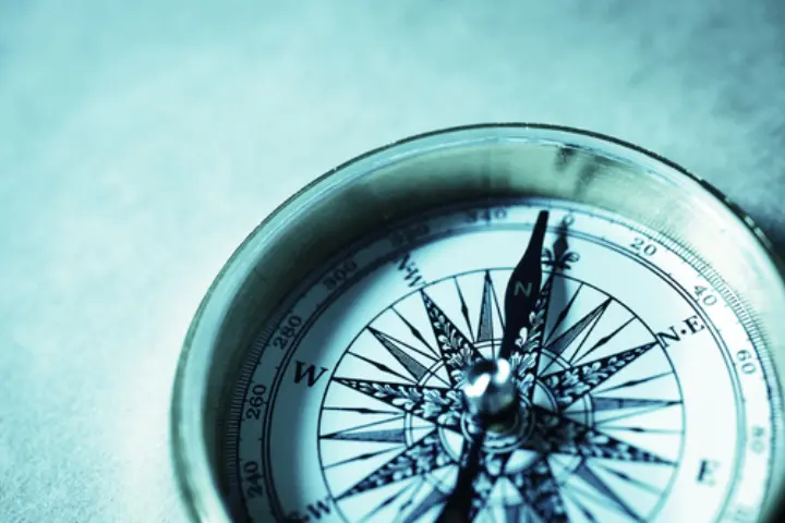 A close-up of a metal compass showing cardinal directions, with the needle pointing toward the north—symbolizing direction and clarity, much like a successful Discovery Call.