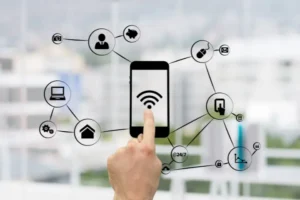 A hand touches a smartphone screen with a Wi-Fi symbol, surrounded by icons representing various connected devices and services, symbolizing smart technology and connectivity.